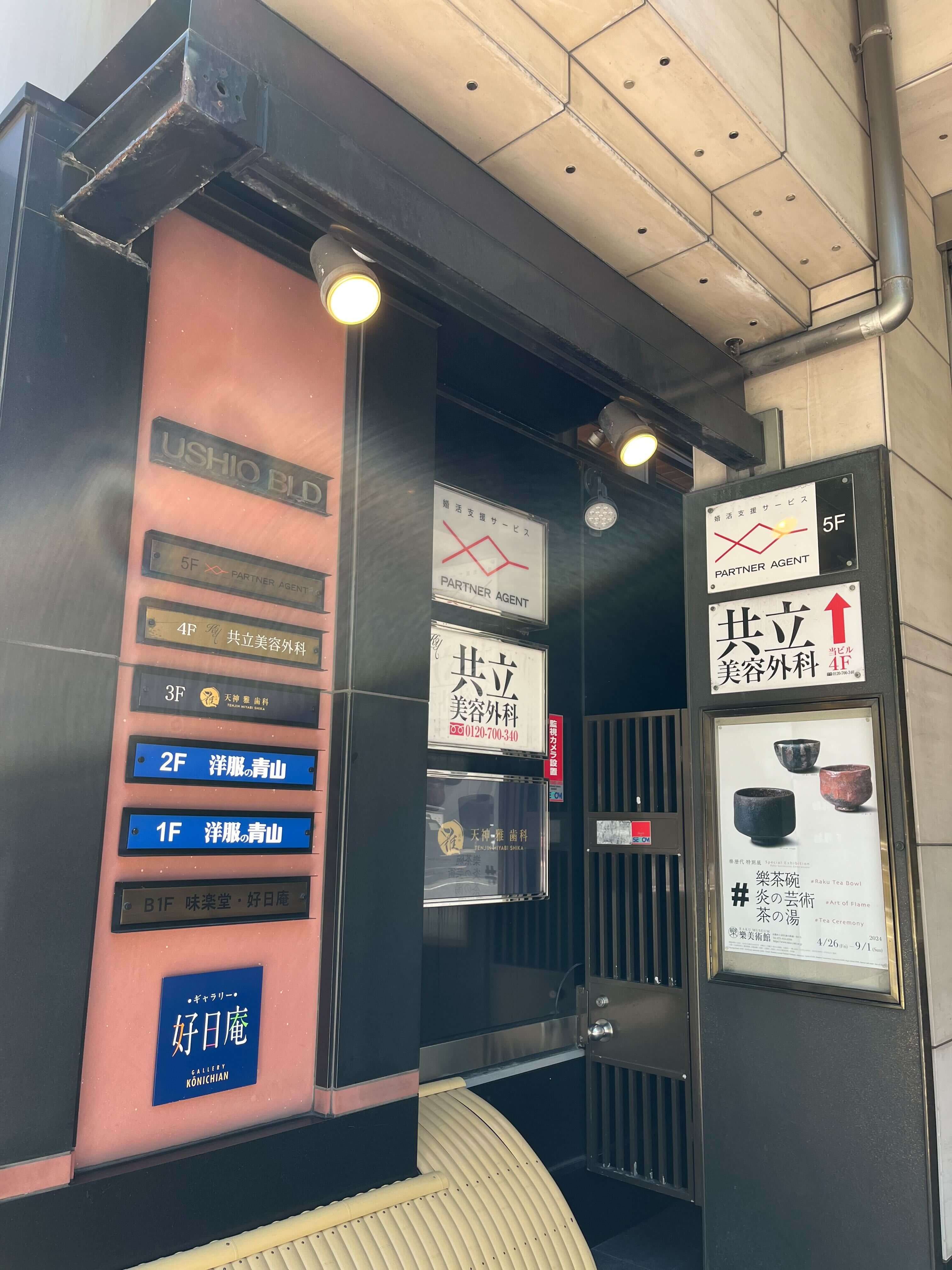 ⑥到着 USHIOビルの入り口です。看板が左手に見えます。エレベーターで4Fまでお越し下さい。（